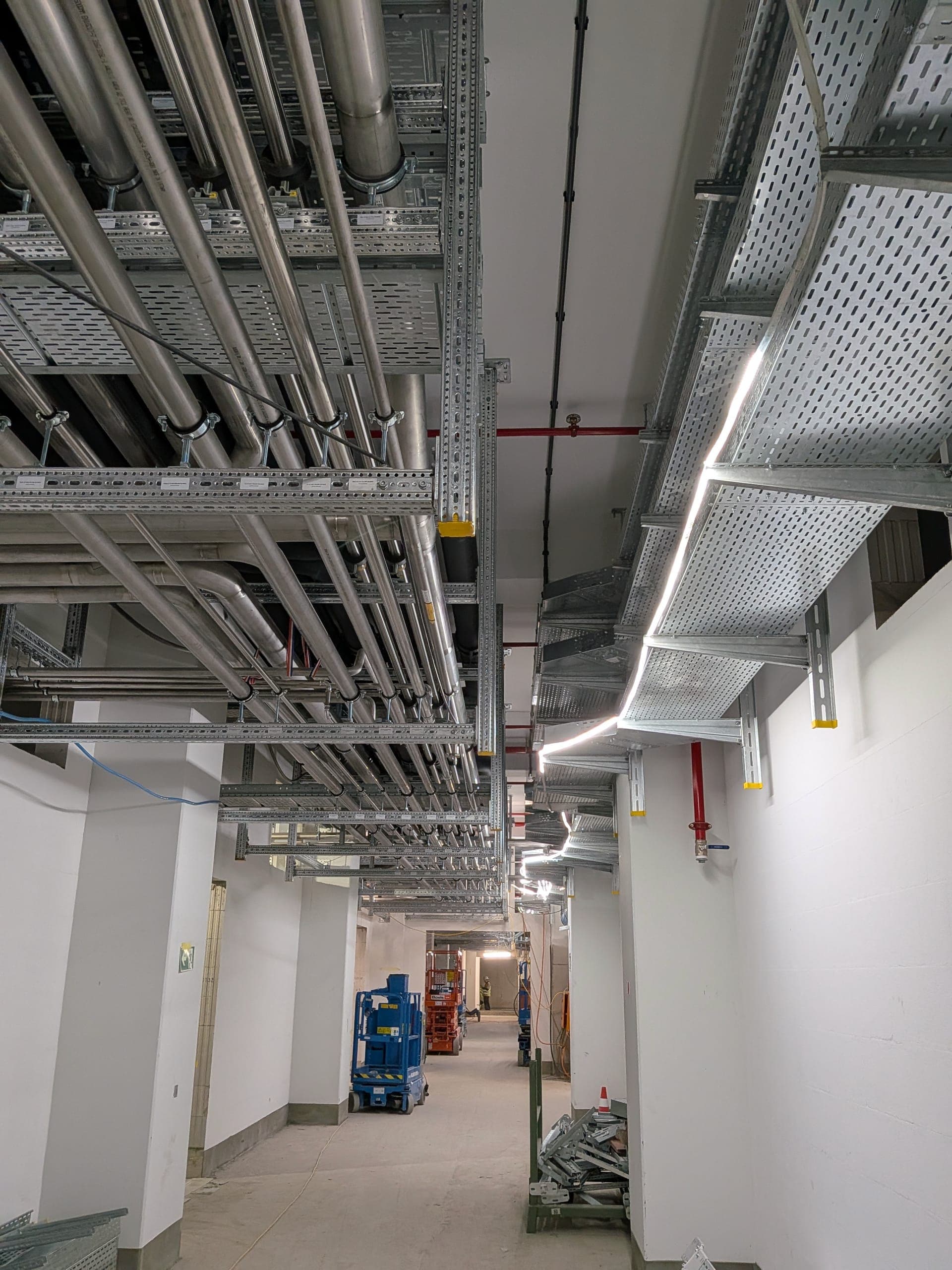 Installationskorridor mit Kabeltrassen und Leitungen auf der Baustelle
